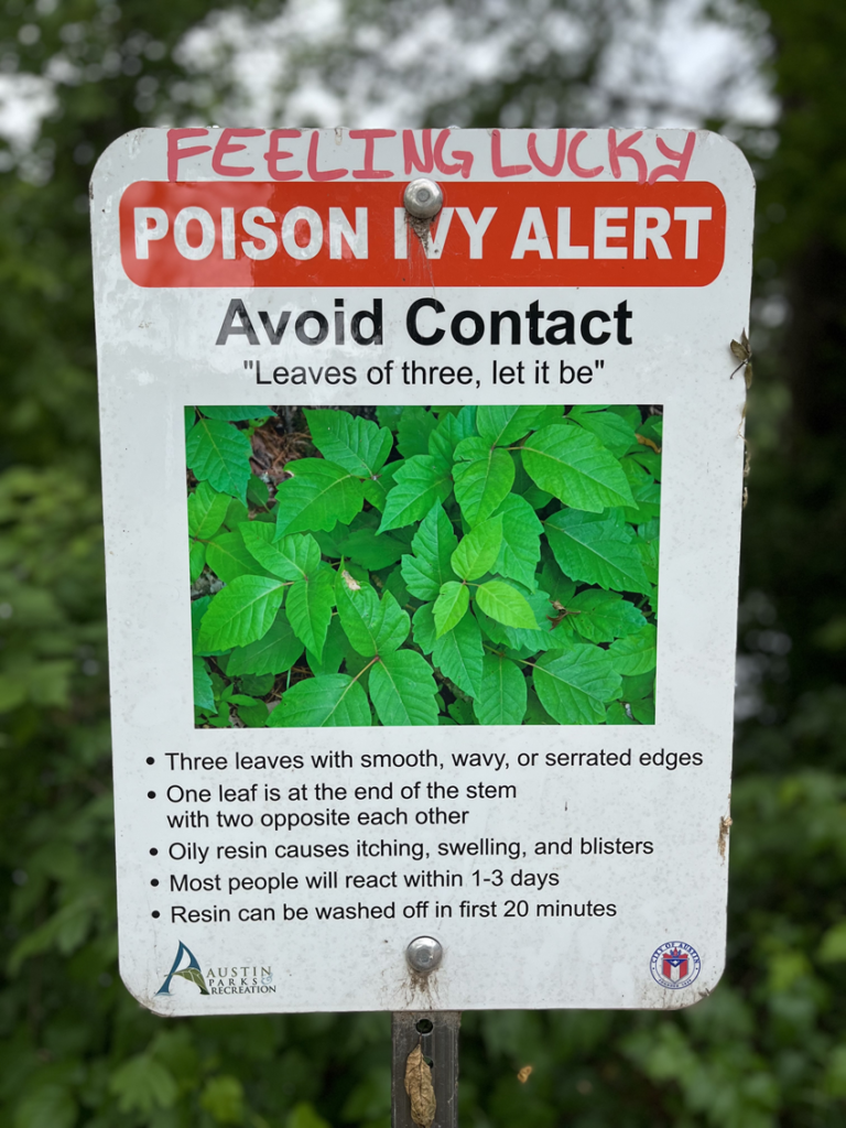 Photograph taken along Town Lake Trail in Austin, Texas. Sign reads: Poison Ivy Alert. Avoid Contact.